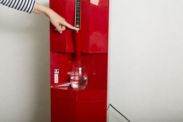 本体のボタンを押し、グラスに水を注いでいる写真