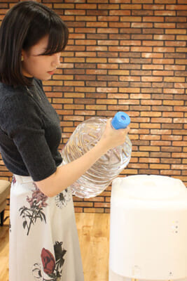 女性が信濃湧水サーバーのボトル交換をする写真